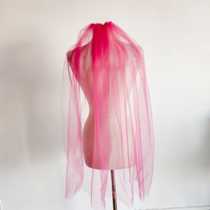 May include: A pink tulle bridal veil on a white mannequin.
