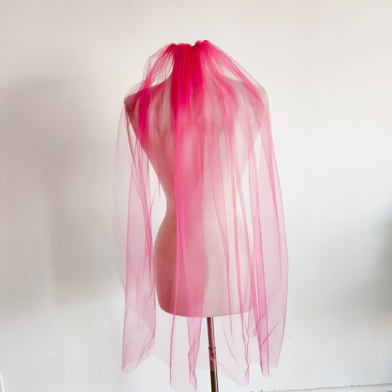 May include: A pink tulle bridal veil on a white mannequin.