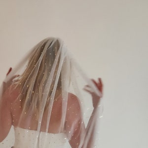 Op de afbeelding: Een witte bruids sluier met gouden glittersterren die over de hele sluier zijn verspreid. De sluier is doorschijnend en delicaat, en de sterren voegen een vleugje glans toe.