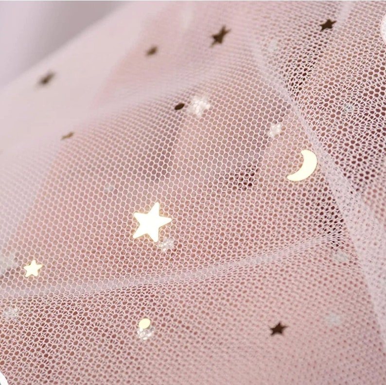 Op de afbeelding: Roze tule stof met gouden glittersterren en een halve maan.