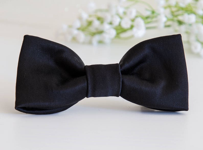 May include: A black bow tie made of satin fabric.