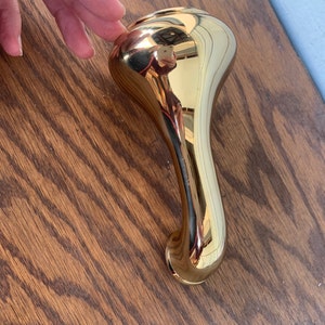May include: A gold-toned metal bathtub spout with a curved design.