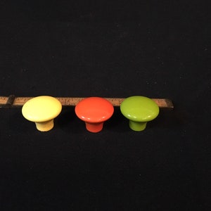 May include: Three ceramic cabinet knobs in yellow, orange, and green.