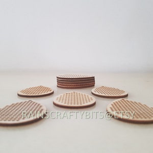 May include: A collection of unfinished wooden coasters with a perforated design. The coasters are round with a small hole at the top for hanging. The text "RAINS CRAFTY BITS @ ETSY" is visible on the bottom of the image.