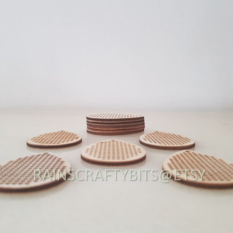 May include: A collection of unfinished wooden coasters with a perforated design. The coasters are round with a small hole at the top for hanging. The text "RAINS CRAFTY BITS @ ETSY" is visible on the bottom of the image.