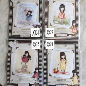 May include: Four counted cross stitch patterns featuring illustrations of a girl with a red umbrella, a girl with a red dress, a girl with a yellow dress and a dog, and a girl with a blue dress. Each pattern is labelled "gorjuss" and "Bothy Threads".