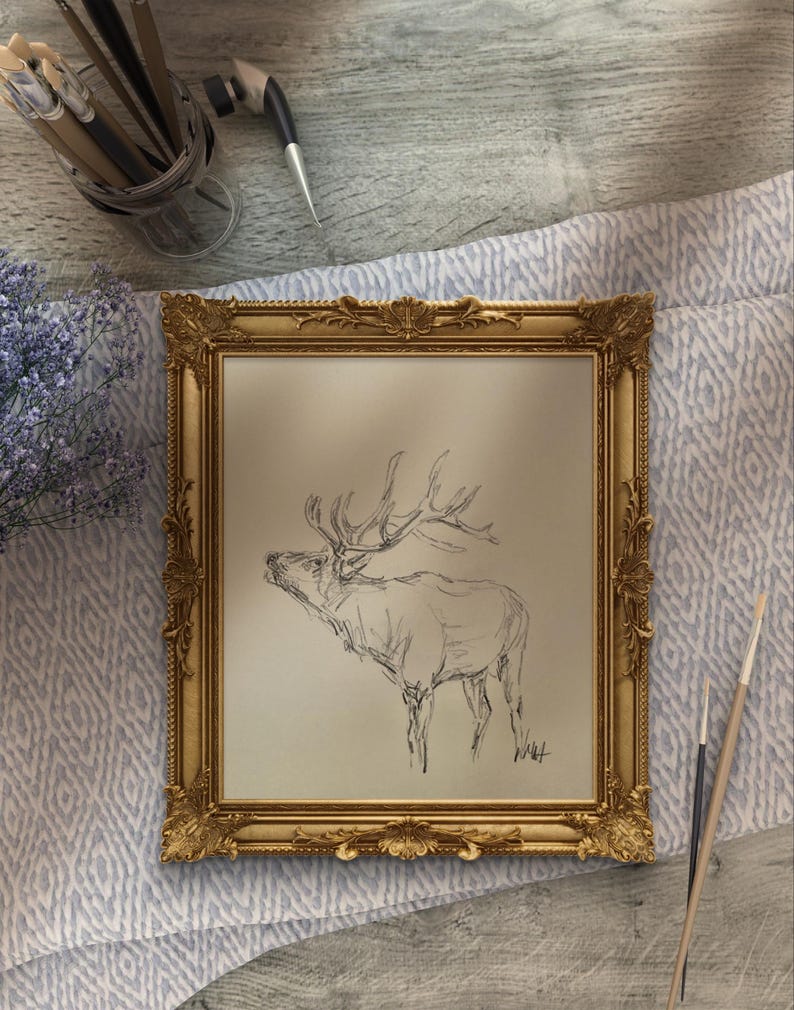 May include: A framed black and white pencil sketch of an elk with large antlers, set against a light beige background. The frame is ornate and gold in color.