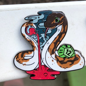 May include: A white and brown snake with a green 12-sided die, wrapped around a red liquid that is dripping from a small red orb. The snake has a green eye and a black tongue. The background is a blue and white swirl.