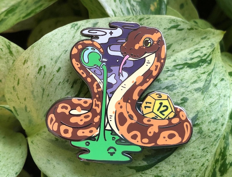 May include: A brown and orange snake with a green and purple background. The snake is holding a yellow 12-sided die. The snake is wearing a green and purple hat.
