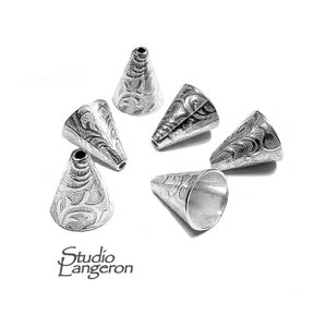 May include: Six silver cone-shaped metal beads with an intricate floral design. The beads are approximately 2.5 cm in length.
