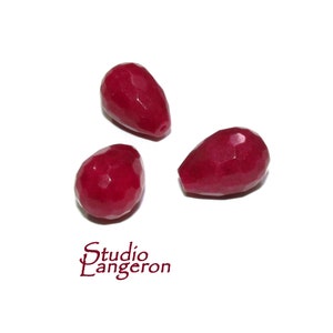 Puede incluir: Tres cuentas facetadas en forma de lágrima de color rojo intenso. Las cuentas están hechas de vidrio o piedra preciosa y tienen un acabado pulido.