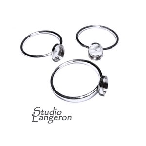 Op de afbeelding: Drie zilveren ringen met een heldere glazen bezel-setting. De ringen zijn ontworpen om een kleine cabochon-steen te bevatten.