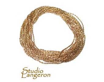 May include: A gold chain necklace coiled into a circle. The chain is made of a twisted rope design.