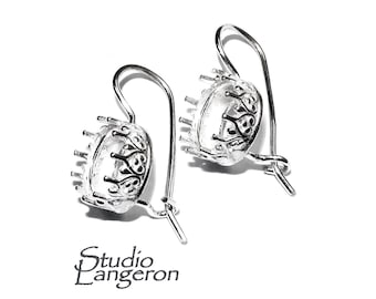 May include: A pair of silver earring settings with a delicate, ornate design. The settings are designed to hold a round stone or cabochon.