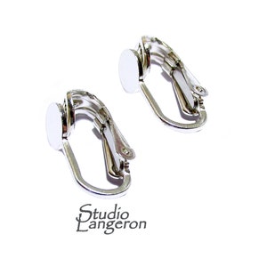 May include: A pair of silver clip-on earring findings with round, flat pads. The pads are smooth and have a shiny finish.