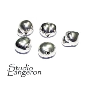 Puede incluir: Cinco cuentas de plata con un agujero en el centro. Las cuentas tienen una forma irregular y un acabado liso y brillante.