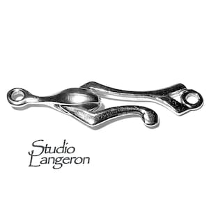 Op de afbeelding: Zilverkleurige metalen sluiting met een uniek, abstract ontwerp. De sluiting heeft aan beide uiteinden twee lussen om aan een ketting of armband te bevestigen.