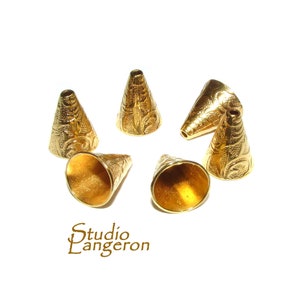 May include: Six gold-coloured metal cone-shaped beads with a decorative floral pattern. The beads have a smooth, shiny finish.