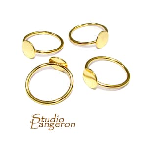 May include: Four gold-toned rings with a round, flat disc on each. The rings are simple and minimalist.