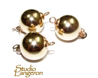 May include: Three gold-toned metal clasps for a necklace or bracelet. Each clasp is a round ball with a loop on one side and a hook on the other.