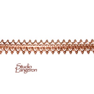 May include: A copper-colored metal trim with a repeating heart design. The trim is about 1/2 inch wide.
