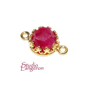 May include: Gold-tone connector with a red gemstone set in a crown-like design. The connector has two loops for attaching to jewellery.