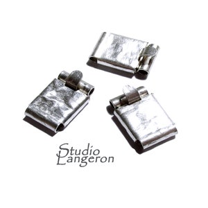 Puede incluir: Tres cierres de metal plateado con un diseño de bisagra. Cada cierre tiene una forma rectangular con un borde ligeramente curvado.