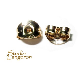 May include: Two gold-toned earring backs. The back on the left has the inscription "14K" on the back.