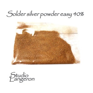 Könnte beinhalten: Ein durchsichtiger Plastikbeutel gefüllt mit einem braunen, feinkörnigen Pulver, beschriftet mit "Solder silver powder easy 40%".