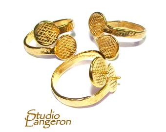 May include: Three gold rings with a textured surface and a round, open bezel setting. The rings are designed to hold a cabochon stone.