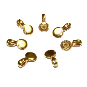 May include: Eight gold-tone metal pendant bails with a loop on one end and a flat disc on the other. The bails are arranged in a circle on a white background.