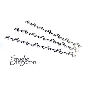 Puede incluir: Tres cadenas de plata con un patrón de eslabones ovalados repetidos. Las cadenas están dispuestas en forma escalonada sobre una superficie blanca. El texto "Studio Langeron" es visible en la esquina inferior izquierda de la imagen.