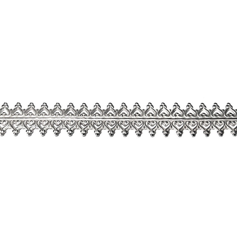 Peut inclure: Garniture argent&eacute;e avec un motif de c&oelig;ur r&eacute;p&eacute;t&eacute;. La garniture est en m&eacute;tal et a une finition brillante.