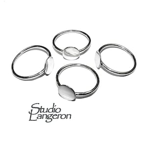 Könnte beinhalten: Vier silberne Ringe mit minimalistischem Design. Jeder Ring hat ein dünnes Band und eine kleine, oval geformte Silberplatte. Die Ringe werden auf einer weißen Oberfläche präsentiert. Das Studio Langeron-Logo ist unten links sichtbar.