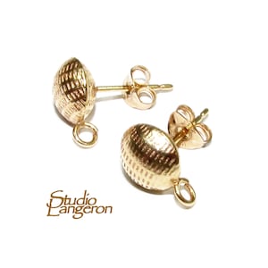 May include: A pair of gold-tone earring findings with a textured, oval-shaped design. Each finding has a loop at the bottom and a post with a butterfly clasp.