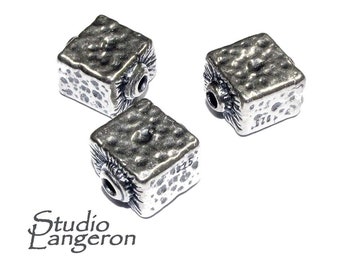 May include: Three silver square beads with a textured surface. The beads have a hole in the center for stringing.
