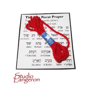 Puede incluir: Cordón rojo con una tarjeta de oración hebrea. La tarjeta presenta el texto "The Porat Prayer" y una oración hebrea. El cordón está atado con una cinta azul con una estrella de David blanca.