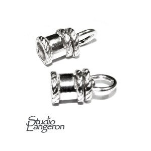 May include: Two silver metal cord end caps with a rope design. The caps have a small loop at the top.
