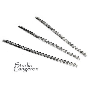 May include: Three silver metal trim pieces with a geometric pattern. The trim pieces are straight and have a jagged edge.