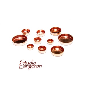 May include: Assortment of copper cabochon settings in various sizes. The settings are round and have a smooth, polished finish.