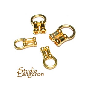 May include: Four gold-toned metal clasps for jewelry making. Each clasp has a round loop and two cylindrical bars.