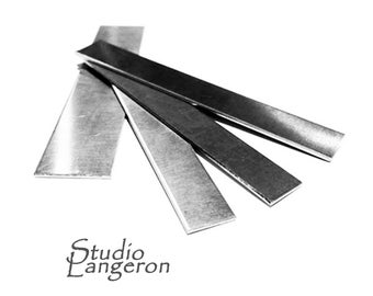 Puede incluir: Cuatro tiras de metal plateado apiladas una encima de la otra. Las tiras son rectangulares y tienen un acabado cepillado.