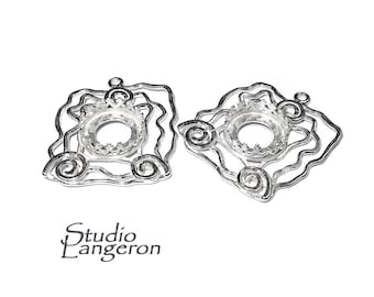 Puede incluir: Dos blanks para pendientes de metal plateado con forma cuadrada y una abertura redonda en el centro. Los blanks tienen un diseño decorativo de espirales y curvas.