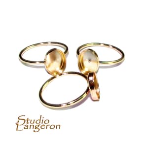 May include: Three gold-toned rings with round bezels. The bezels are open on the back and are designed to hold a cabochon stone.