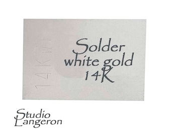 May include: A white label with black text that reads "Solder white gold 14K". The label also has the text "14K" written vertically on the left side. The text "Studio Langeron" is printed below the label.