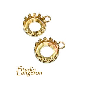 May include: Two gold-tone metal crown-shaped pendant settings with a round opening for a stone or cabochon. Each setting has a small loop at the top for attaching a chain or cord.