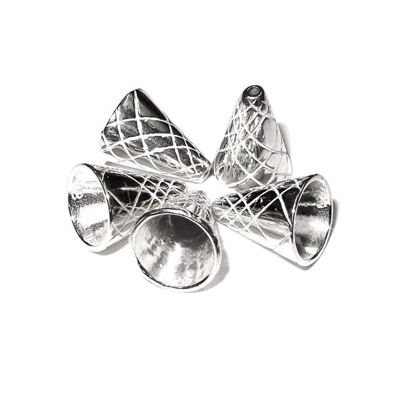 Op de afbeelding: Vijf zilveren metalen kegelvormige kralencaps met een kruislings patroon. De caps zijn in een cirkel op een witte achtergrond gerangschikt.