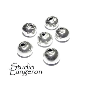 May include: Six silver metal beads with a hole in the center. The beads have a textured surface.