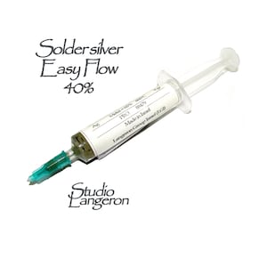 Könnte beinhalten: Eine transparente Plastikspritze gefüllt mit silberfarbener Lötpaste. Das Etikett lautet "Solder silver Easy Flow 40% Metal-60% 600°C PRO 88479 Made in Israel Langeron Group Israel (LGI)"