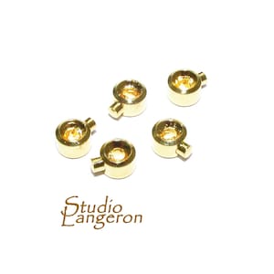 May include: Five gold-coloured metal rings with a small protruding tab on each ring. The rings are designed for use in jewellery making or other crafts.